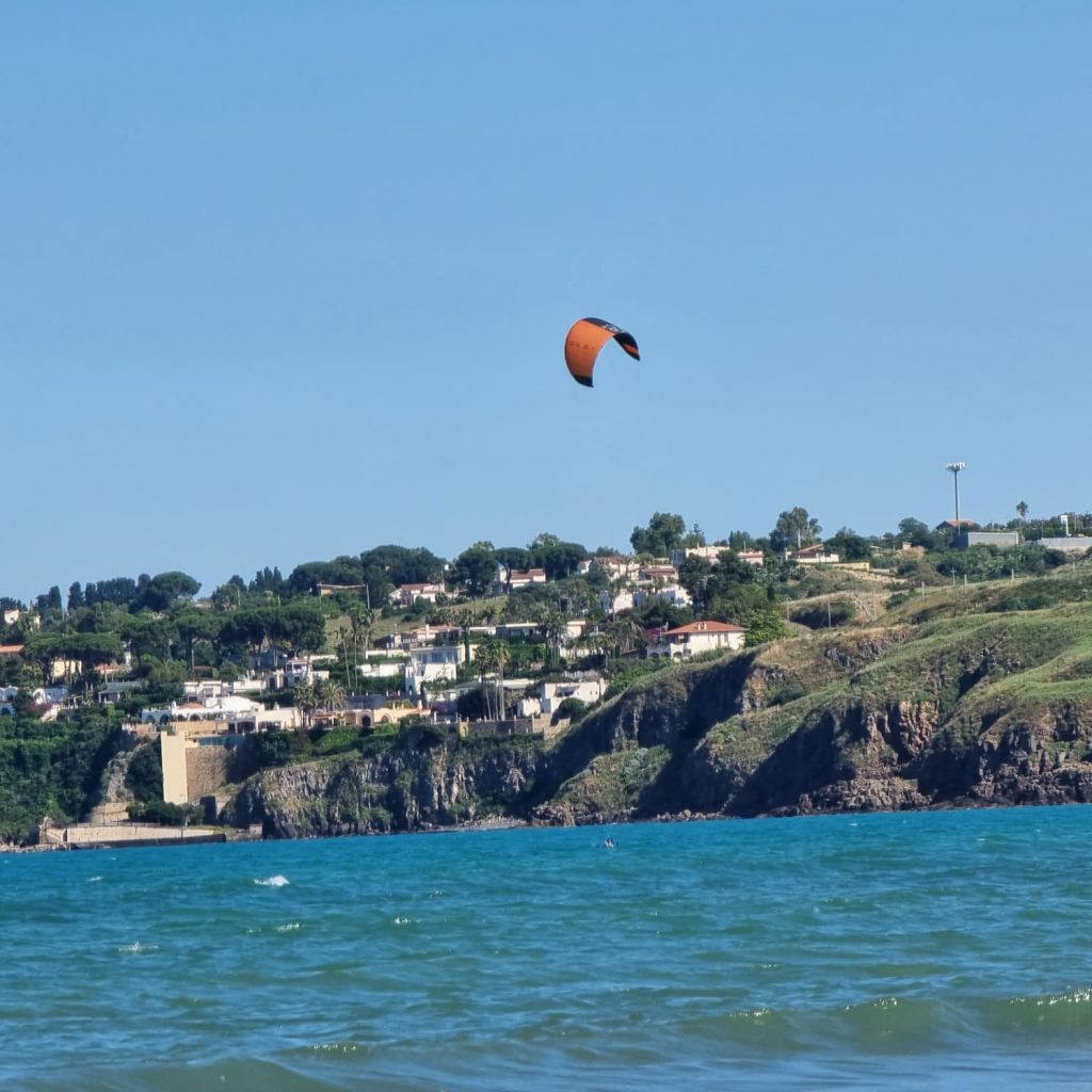 🇮🇹 Italiano Kitesurf sulla costa di Agnone Bagni in una giornata ventosa perfetta per sport a vela. 🇬🇧 English Kitesurfing along the windy shores of Agnone Bagni, ideal for sailing sports in Sicily. 🇩🇪 Deutsch Kitesurfer vor der Küste von Agnone Bagni – perfekte Bedingungen bei Scirocco-Wind. 🇫🇷 Français Pratique du kitesurf à Agnone Bagni, lieu propice aux sports nautiques avec le vent du sud. 🇨🇿 Čeština Kitesurfing u pobřeží Agnone Bagni – oblast známá silným poledním větrem. 🇧🇬 Български Кайтсърфинг край бреговете на Аньоне Бани – идеален вятър за водни спортове. 🇵🇱 Polski Kitesurf na wodach Agnone Bagni – doskonałe warunki dzięki wiatrowi sirocco. 🇧🇷 Português (BR) Kitesurf nas águas de Agnone Bagni com vento perfeito do meio-dia para esportes náuticos. 🇹🇷 Türkçe Agnone Bagni kıyılarında öğle vakti rüzgarıyla kitesurf keyfi – Sicilya'nın rüzgarlı noktası. 🇬🇷 Ελληνικά Kitesurf στην παραλία Agnone Bagni – ιδανικές συνθήκες μεσημεριανού σιρόκου. 🇵🇹 Português (PT) Kitesurf na costa de Agnone Bagni, com vento do sul ideal para desportos à vela. 🇪🇸 Español Kitesurf frente a la costa de Agnone Bagni, con viento perfecto del sur al mediodía.