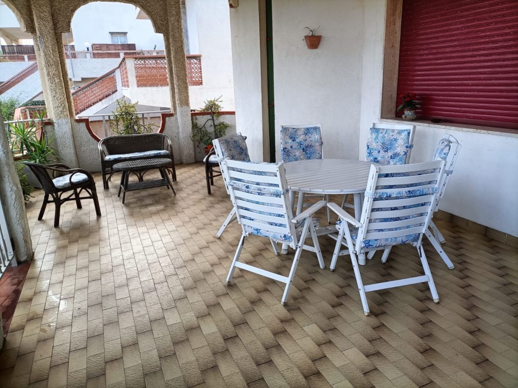Lingua Testo 🇮🇹 IT Terrazza coperta con tavolo rotondo, sedie bianche e zona salotto all’aperto 🇬🇧 EN Covered terrace with round table, white chairs and outdoor seating area 🇩🇪 DE Überdachte Terrasse mit rundem Tisch, weißen Stühlen und Sitzbereich 🇫🇷 FR Terrasse couverte avec table ronde, chaises blanches et coin salon extérieur 🇨🇿 CZ Krytá terasa s kulatým stolem, bílými židlemi a venkovním posezením 🇧🇬 BG Покрита тераса с кръгла маса, бели столове и кът за сядане на открито 🇵🇱 PL Zadaszony taras z okrągłym stołem, białymi krzesłami i miejscem do siedzenia 🇧🇪 NL Overdekt terras met ronde tafel, witte stoelen en zithoek buiten 🇹🇷 TR Yuvarlak masa, beyaz sandalyeler ve açık hava oturma alanıyla kapalı teras 🇬🇷 GR Σκεπαστή βεράντα με στρογγυλό τραπέζι, λευκές καρέκλες και καθιστικό 🇵🇹 PT Terraço coberto com mesa redonda, cadeiras brancas e área de estar ao ar livre 🇪🇸 ES Terraza cubierta con mesa redonda, sillas blancas y zona de estar exterior 🏷️ Titolo SEO Lingua Titolo 🇮🇹 IT Zona relax e pranzo sulla terrazza coperta – Fortezza Villa Azzurra 🇬🇧 EN Dining and lounge area on the covered terrace – Fortezza Villa Azzurra 🇩🇪 DE Ess- und Ruhebereich auf überdachter Terrasse – Fortezza Villa Azzurra 🇫🇷 FR Coin repas et détente sur terrasse couverte – Fortezza Villa Azzurra 🇨🇿 CZ Jídelní a odpočinkový kout na kryté terase – Fortezza Villa Azzurra 🇧🇬 BG Зона за хранене и отдих на покрита тераса – Fortezza Villa Azzurra 🇵🇱 PL Jadalnia i strefa relaksu na zadaszonym tarasie – Fortezza Villa Azzurra 🇧🇪 NL Eet- en loungehoek op overdekt terras – Fortezza Villa Azzurra 🇹🇷 TR Kapalı terasta yemek ve dinlenme alanı – Fortezza Villa Azzurra 🇬🇷 GR Τραπεζαρία και χώρος χαλάρωσης στη σκεπαστή βεράντα – Fortezza Villa Azzurra 🇵🇹 PT Zona de refeições e relaxamento no terraço coberto – Fortezza Villa Azzurra 🇪🇸 ES Zona de comedor y relax en terraza cubierta – Fortezza Villa Azzurra 🖼️ Didascalia | 🇮🇹 IT | Un’area fresca e protetta per mangiare, rilassarsi o lavorare all’aria aperta. | | 🇬🇧 EN | A cool, sheltered area to eat, relax or even work outdoors. | | 🇩🇪 DE | Kühle, überdachte Fläche zum Essen, Entspannen oder Arbeiten im Freien. | | 🇫🇷 FR | Espace frais et ombragé pour manger, se détendre ou télétravailler. | | 🇨🇿 CZ | Příjemné, kryté místo na jídlo, odpočinek nebo práci venku. | | 🇧🇬 BG | Прохладно и покрито място за хранене, почивка или работа на открито. | | 🇵🇱 PL | Chłodne, zadaszone miejsce na posiłek, odpoczynek lub pracę na świeżym powietrzu. | | 🇧🇪 NL | Koele, beschutte plek om te eten, ontspannen of buiten te werken. | | 🇹🇷 TR | Yemek yemek, dinlenmek ya da dışarıda çalışmak için gölgeli serin alan. | | 🇬🇷 GR | Δροσερός σκεπαστός χώρος για φαγητό, χαλάρωση ή εργασία σε εξωτερικό χώρο. | | 🇵🇹 PT | Espaço coberto e fresco para refeições, relaxamento ou teletrabalho. | | 🇪🇸 ES | Zona fresca y protegida para comer, relajarse o trabajar al aire libre. | 📝 Descrizione SEO estesa 🇮🇹 Italiano La terrazza coperta si presenta come un ambiente multifunzionale: un tavolo rotondo con sedie bianche imbottite accoglie gli ospiti per colazioni, pranzi o momenti di lettura, mentre l’area salotto adiacente offre uno spazio perfetto per conversazioni e relax. Grazie alla copertura e alla brezza naturale, è uno degli angoli più confortevoli della casa, ideale in ogni momento della giornata. 🇬🇧 English The covered terrace is a multifunctional space: a round table with cushioned white chairs welcomes guests for breakfast, lunch, or reading moments, while the adjacent lounge area offers the perfect spot for conversation and relaxation. With its roof and natural breeze, it's one of the most comfortable corners of the house, ideal at any time of day. 🇩🇪 Deutsch Die überdachte Terrasse ist ein vielseitiger Raum: Ein runder Tisch mit gepolsterten weißen Stühlen lädt zum Frühstück, Mittagessen oder Lesen ein. Der angrenzende Lounge-Bereich eignet sich ideal zum Entspannen oder Plaudern. Dank Überdachung und natürlicher Brise ist es einer der angenehmsten Plätze im Haus – zu jeder Tageszeit. 🇫🇷 Français La terrasse couverte est un espace polyvalent : une table ronde avec des chaises blanches rembourrées accueille les hôtes pour les repas ou un moment de lecture, tandis que le coin salon offre un espace propice à la détente. Protégé du soleil et rafraîchi par la brise, c’est l’un des lieux les plus agréables de la maison à toute heure. 🇨🇿 Čeština Krytá terasa slouží jako multifunkční prostor: kulatý stůl s bílými polstrovanými židlemi je ideální pro snídani, oběd nebo čtení, zatímco vedlejší posezení vybízí k odpočinku a rozhovorům. Díky stínu a přirozenému větru jde o jedno z nejpříjemnějších míst v domě během celého dne. 🇧🇬 Български Покритата тераса е многофункционално пространство: кръгла маса с бели възглавнички и зона за сядане предоставят удобство за закуска, обяд или четене. В съседство – място за разговори и отдих. Сянката и леката прохлада я правят едно от най-приятните места в къщата през целия ден. 🇵🇱 Polski Zadaszony taras to wielofunkcyjna przestrzeń: okrągły stół z białymi, miękkimi krzesłami sprzyja śniadaniom, obiadom i relaksowi. Obok znajduje się część wypoczynkowa idealna do rozmów. Osłonięty pr