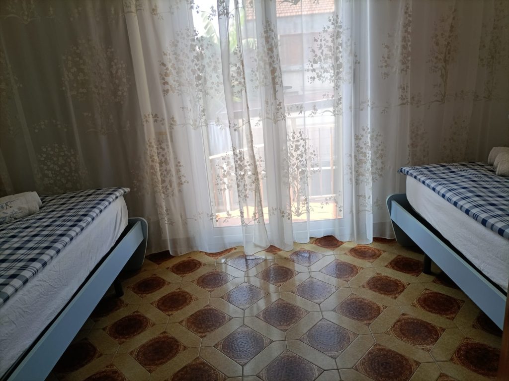 🇮🇹 IT Stanza con due lettini singoli, vista centrale e tende leggere 🇬🇧 EN Twin beds with central view and sheer curtains 🇩🇪 DE Zwei Einzelbetten mit mittlerer Ansicht und leichten Vorhängen 🇫🇷 FR Chambre avec deux lits simples, vue centrale et rideaux légers 🇨🇿 CZ Pokoj se dvěma lůžky, centrální pohled a průsvitné závěsy 🇧🇬 BG Стая с две легла, централна гледка и ефирни завеси 🇵🇱 PL Pokój z dwoma łóżkami, widok na środek i delikatne zasłony 🇧🇪 NL Kamer met twee bedden, zicht tussenin en lichte gordijnen 🇹🇷 TR İki yataklı oda, ortadan görünüm ve tül perdeler 🇬🇷 GR Δωμάτιο με δύο κρεβάτια, κεντρική θέα και διαφανείς κουρτίνες 🇵🇹 PT Quarto com duas camas individuais, vista central e cortinas suaves 🇪🇸 ES Habitación con dos camas, vista central y cortinas translúcidas